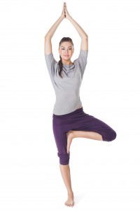 Young woman doing yoga exercise tree-pose isolated on white