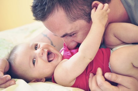 Father playing with his happy and smiling baby daughter
