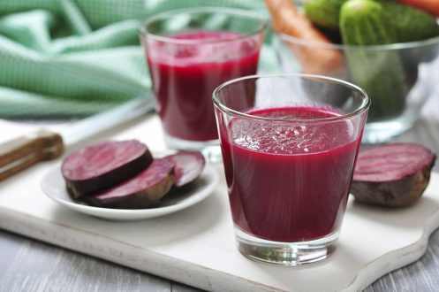 Beetroot juice in glass on wooden cutting board